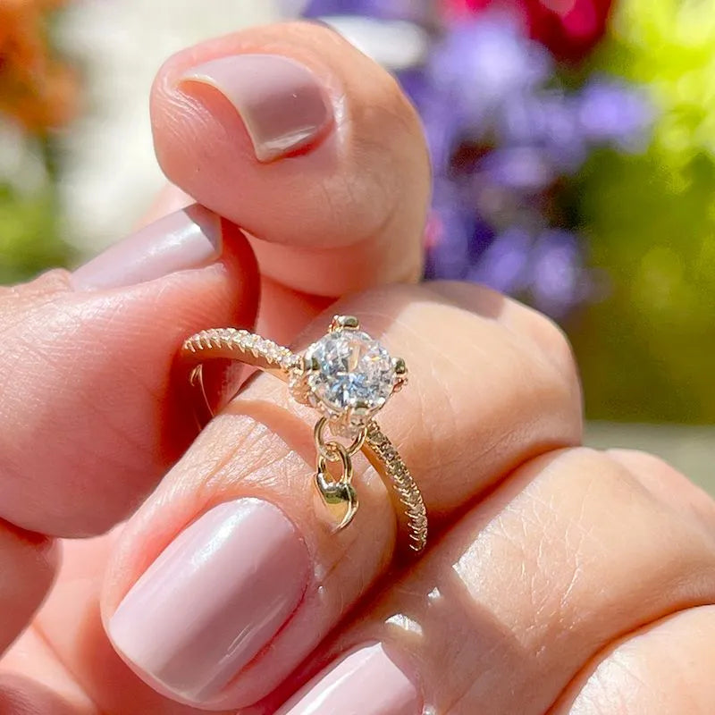 White zirconia solitaire ring with a dangling heart, size 19.